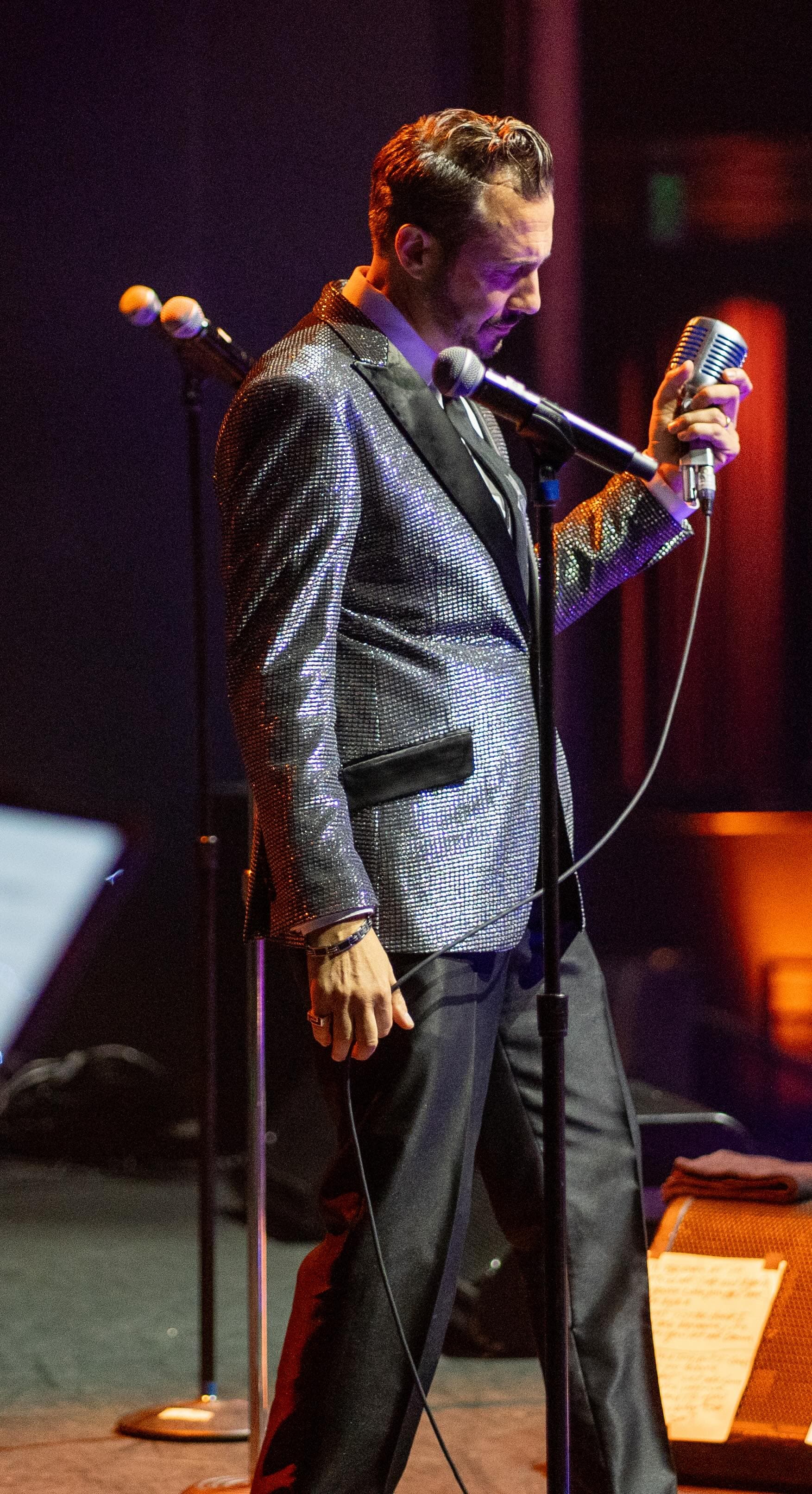 Jimmy G performing on stage with a vintage microphone